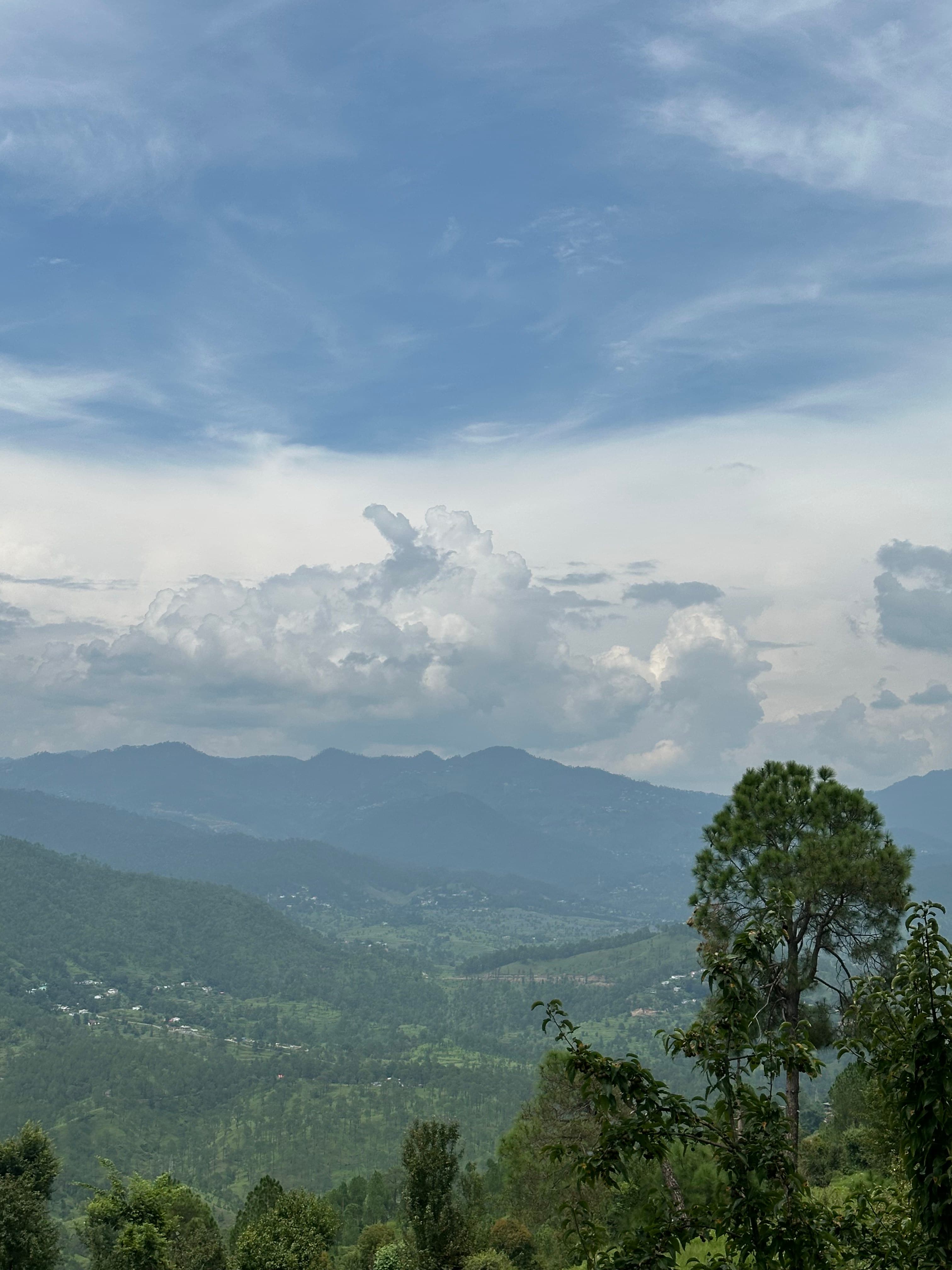 Layered green mountains beneath tall monsoon clouds