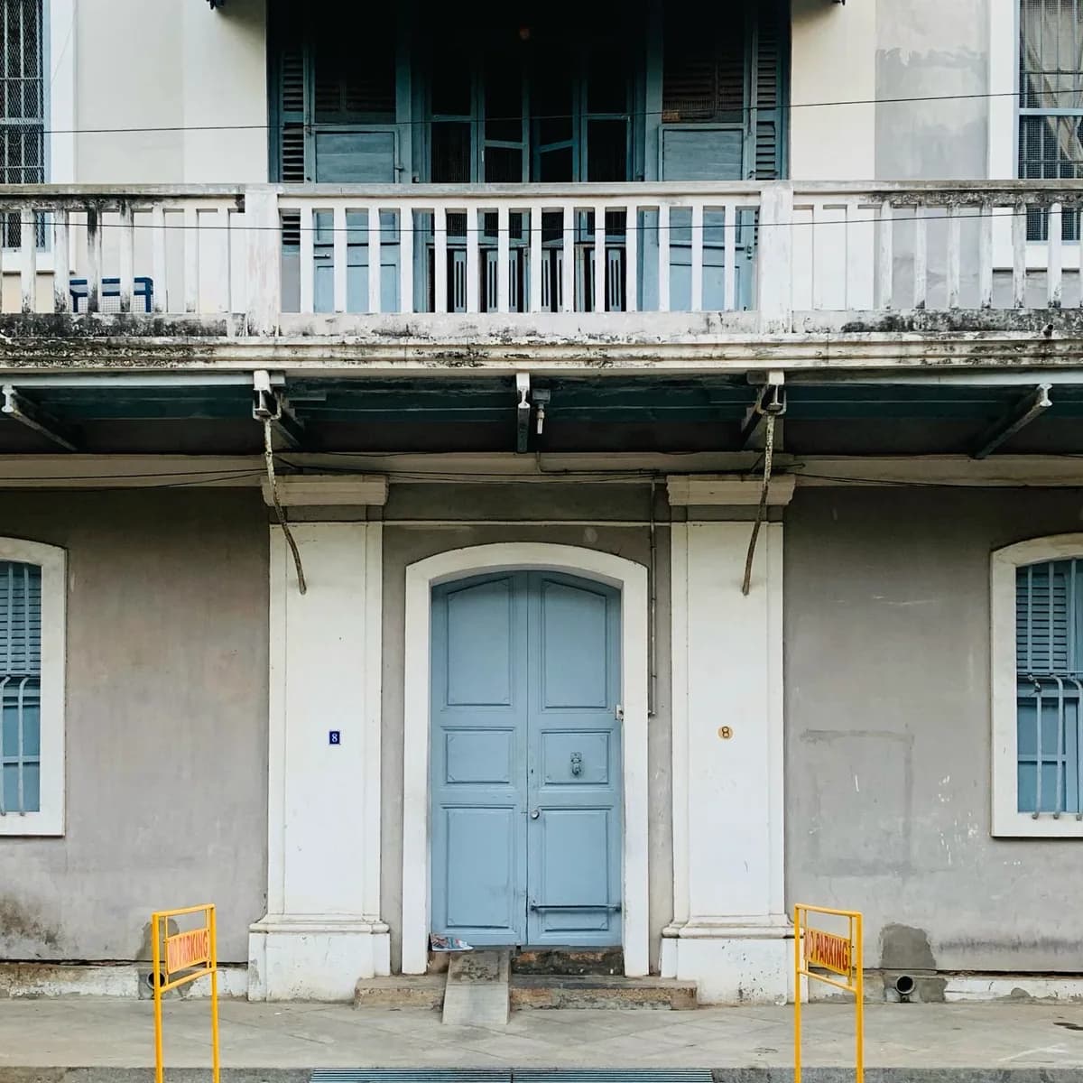 A weathered pale blue and grey colonial facade in White Town